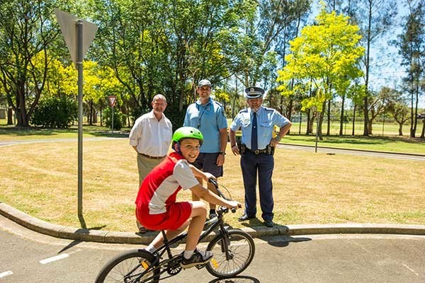 Photo of a young boy on a bike with a police officer and two men behind him. Photo credit: Penrith City Council, NSW