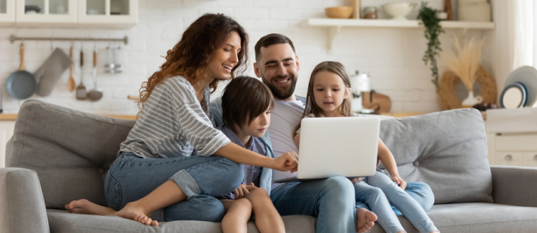 Happy family sitting on a couch using internet device laptop.