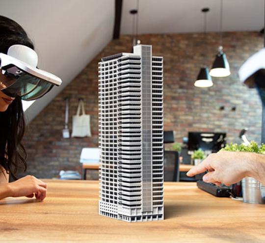 Two people working on virtual 3d building by using Augmented Reality glasses.