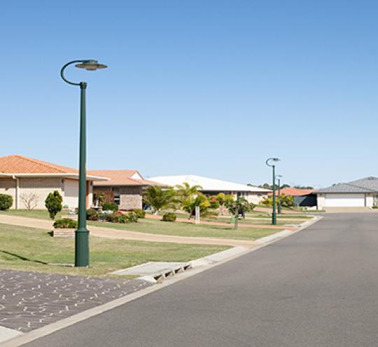 Suburban street showing a road and houses and two street lights.