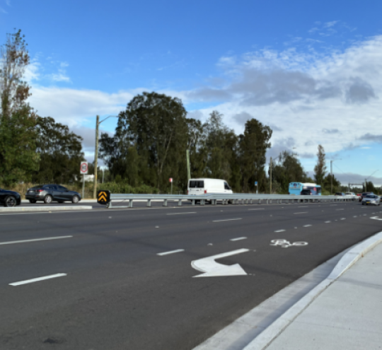 Cars moving along a busy section of road.
