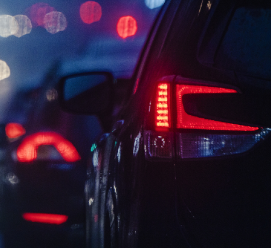 Cars driving in city traffic at night.
