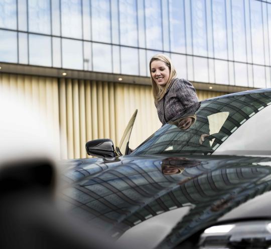 Driver enters electric vehicle in carpark.