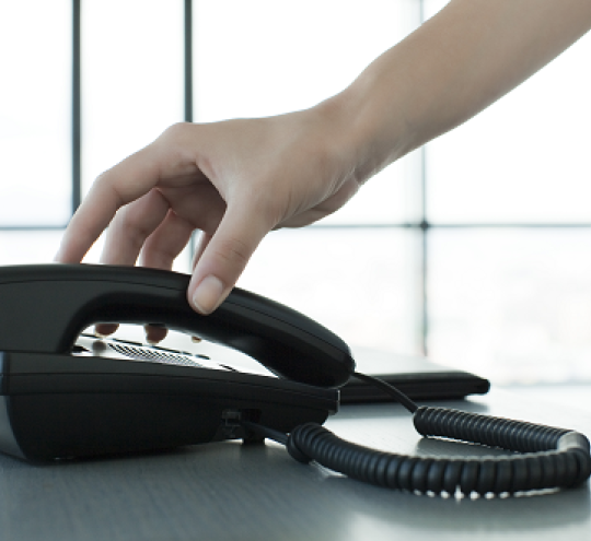 Hand touching a telephone handset.
