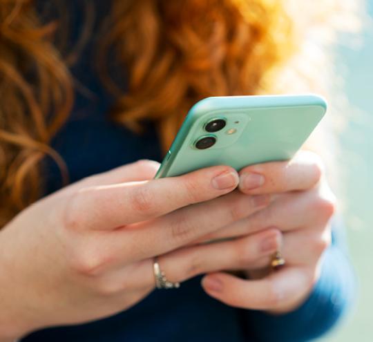 Hands using a green mobile phone device.