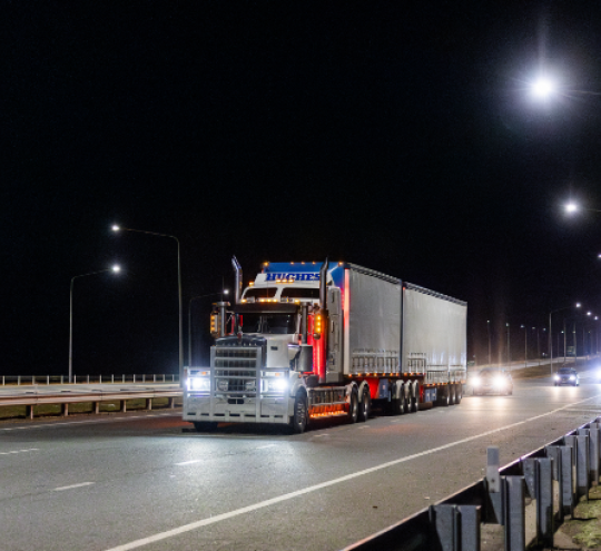 A heavy vehicle driving on a highway at night