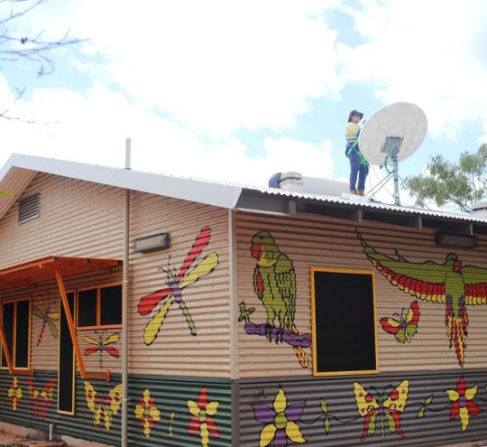 person on roof working on satellite dish