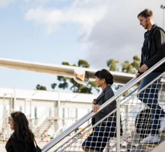 People disebarking a plane down a set of stairs