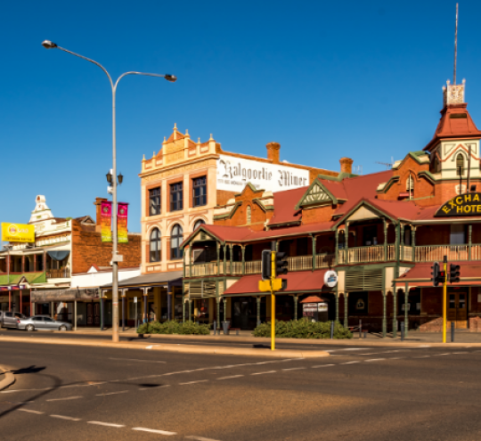 Middle of town centre of Kalgoorlie country town in Australia showing various shop fronts and a hotel.