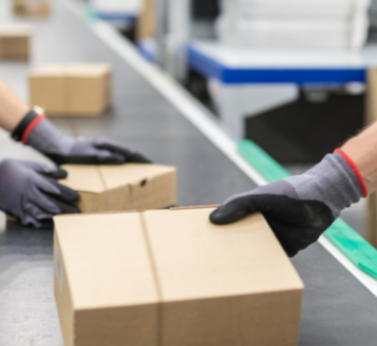 Workers in high visibility clothing handling parcels on a conveyer belt.