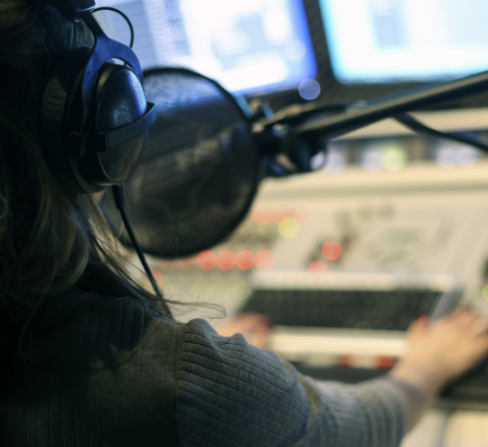 Man sitting in a radio station speaking into a microphone.