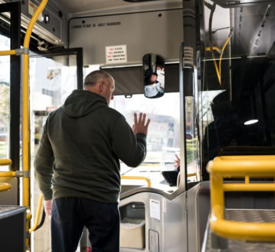 Man waving to bus driver as he exits the bus.