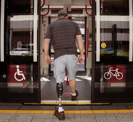 Man with prosthetic leg boards light rail carriage.
