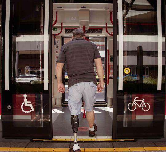 Image of a man with a prosthetic leg boarding a tram.
