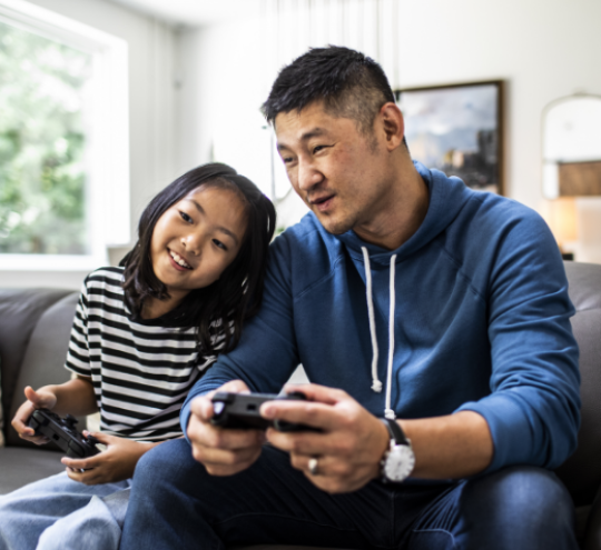 Father And Daughter Playing Video Games At Home
