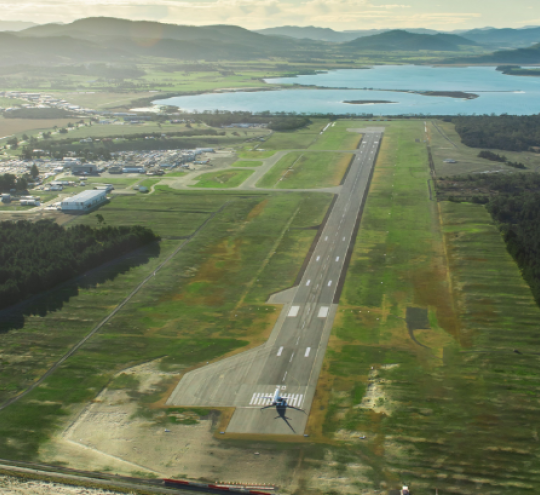 Overhead view of Hobart Airport runway with a plane on the tarmac and hills in the background.