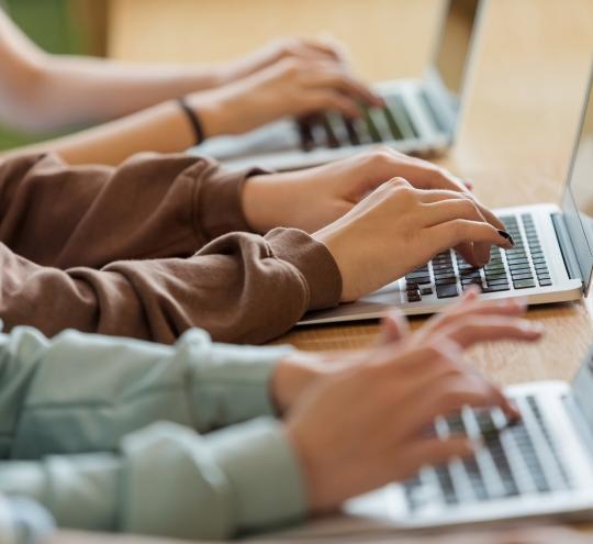 Side profile of children’s arms using laptops.
