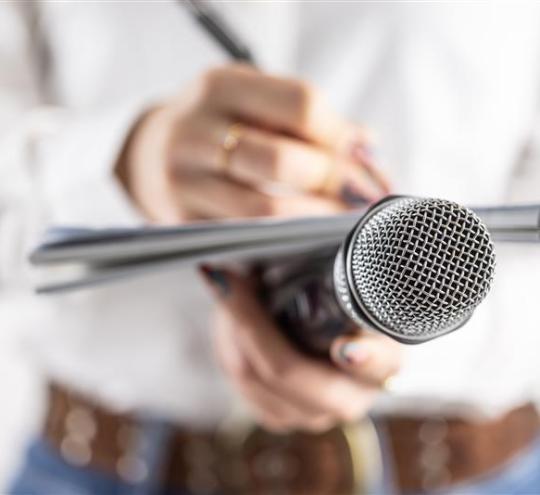 Person holding a microphone and notebook