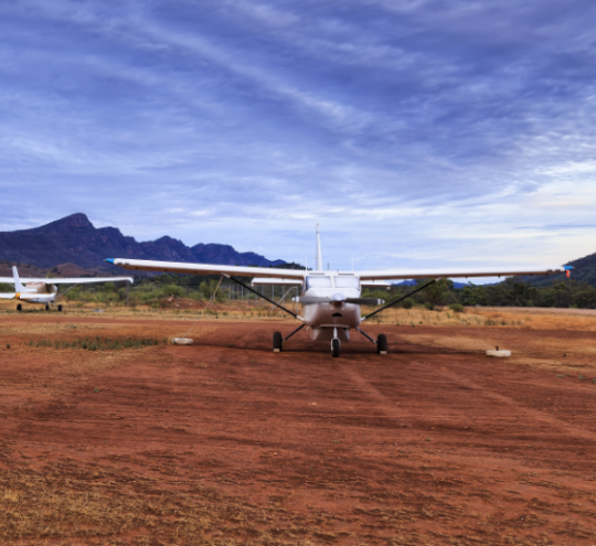 Three light aircraft on a remote Australian airstrip.