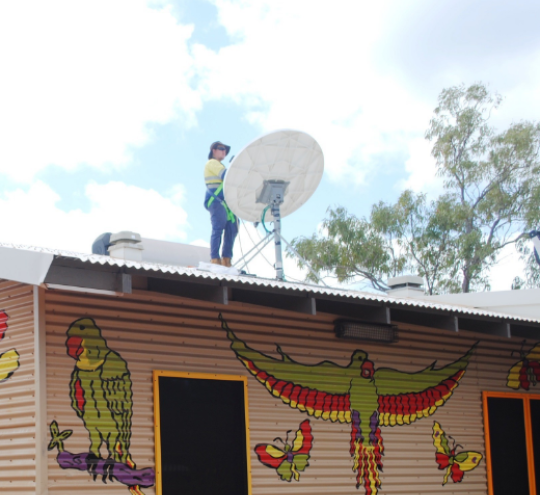 Man standing on top of an evaluation centre roof installing a satellite dish 