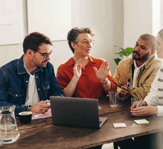 People sitting around a laptop in an office.