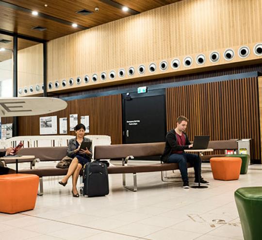 Image depicts persons seated in an airport terminal.