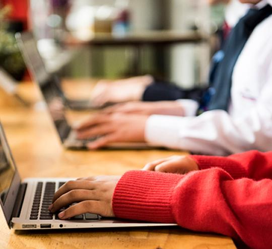 School-aged boy and girl using laptops.