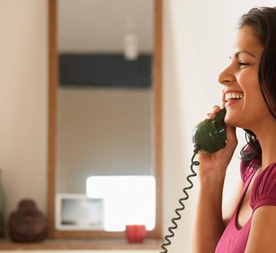 Woman using telephone in hallway.