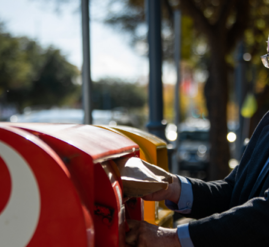 Man posting a letter into an Australia Post mail box.