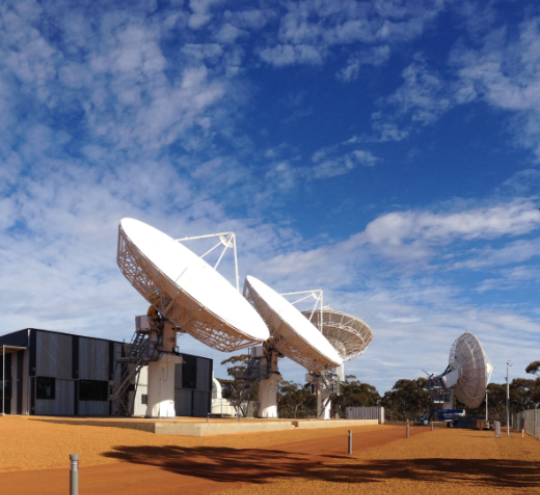 Image of satellite ground station with blue sky and clouds in the background.