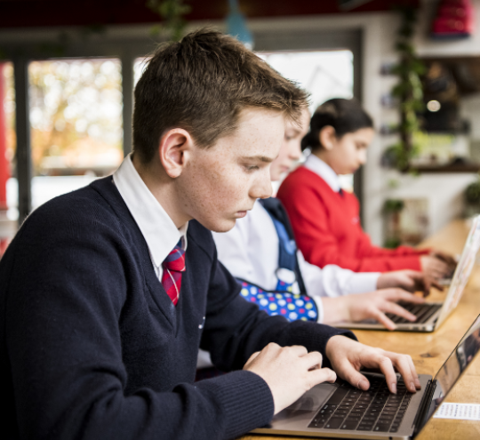 Teenager sitting at a desk with a laptop