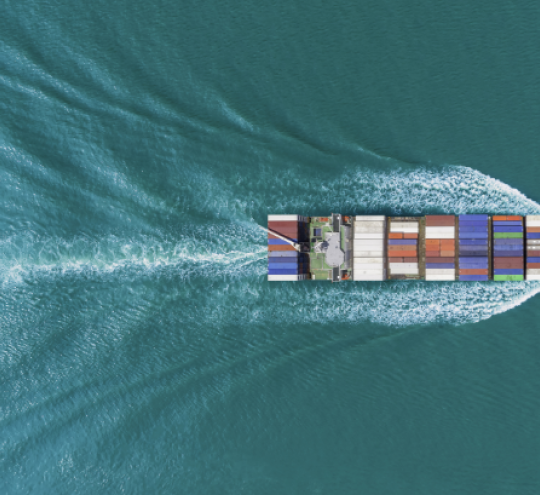 An aerial photo of a large cargo vessel ship moving across the ocean
