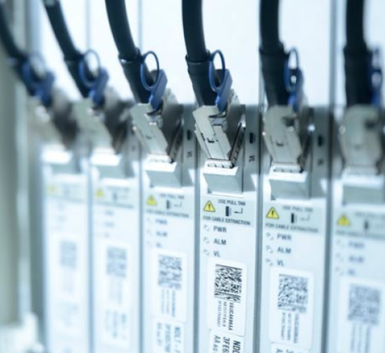 Out of focus image of a row of cables plugged into telecommunications equipment.