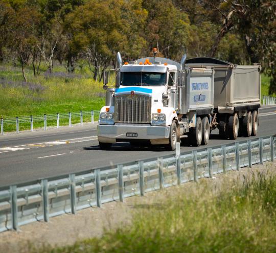 A heavy vehicle driving on a rural road.