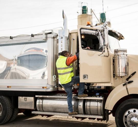 Truck driver enters parked vehicle through driver door.