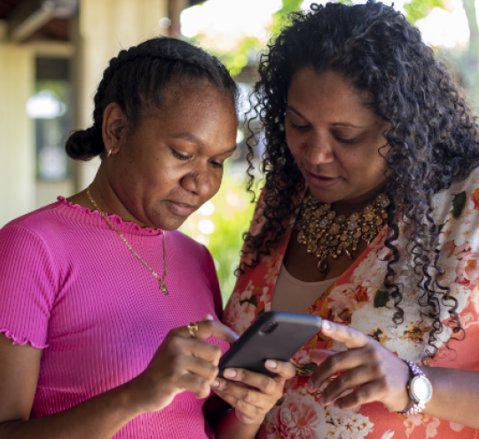 Two First Nations Woman looking at a smart phone.
