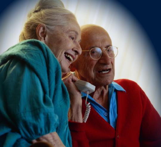 Older couple sharing a handset during a phone call.