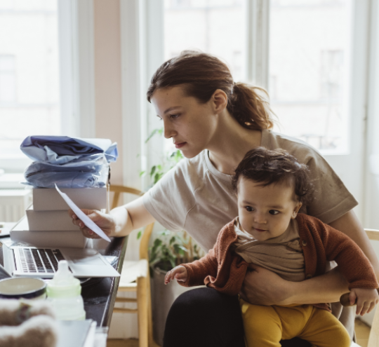 Businesswoman reading document while sitting with baby boy in living room.