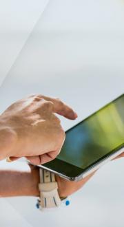 Person using a tablet with their finger on the screen.
