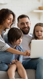 Happy family sitting on a couch using internet device laptop.