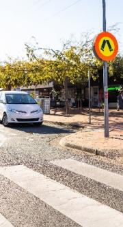 Man who is blind walking across a town centre crosswalk.