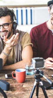 Young adults smiling and laughing sitting around streaming devices on a table.