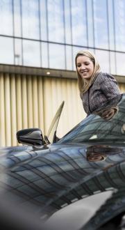 Driver enters electric vehicle in carpark.