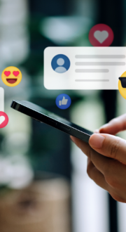 Hands holding smart phone, with emojis and social media comments floating above