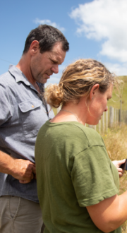 Two farmers in a field looking at information on a tablet device