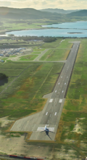 Overhead view of Hobart Airport runway with a plane on the tarmac and hills in the background.