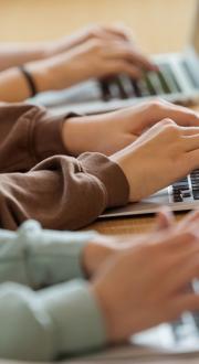 Side profile of children’s arms using laptops.