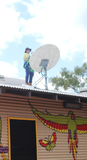 Man standing on top of an evaluation centre roof installing a satellite dish 