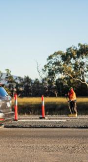 Car passing a construction worker on a regional road