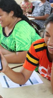 Smiling woman showing the contents of her mobile phone to the camera.